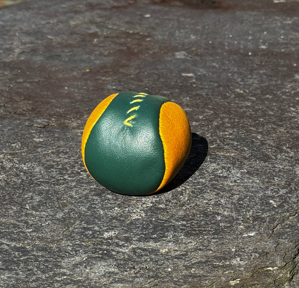 Green and orange footbag on a textured stone surface